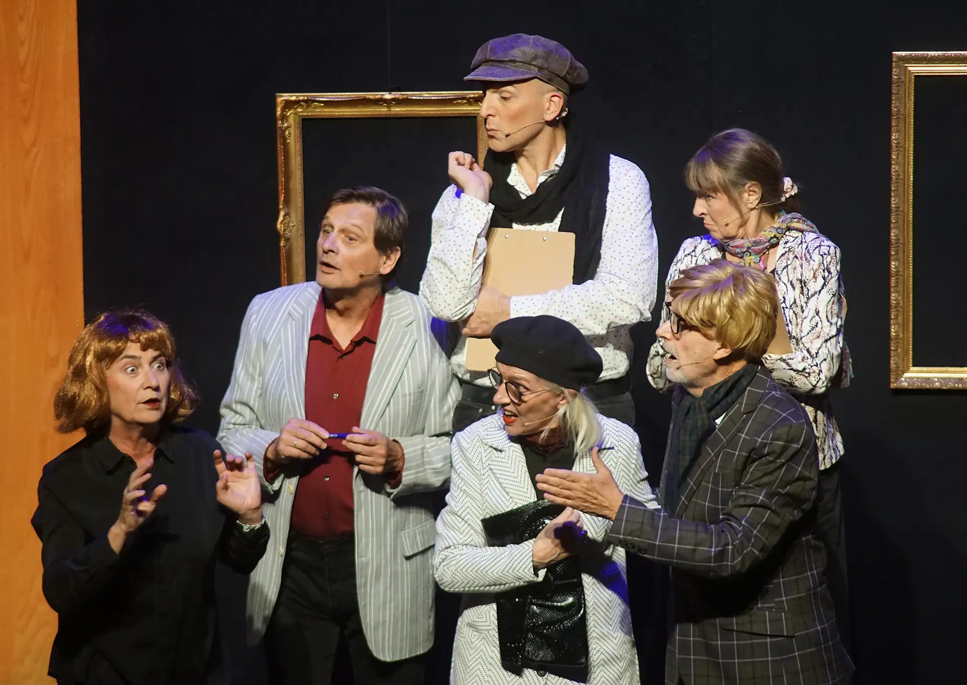Ensemble bei einer Kabarett-/Musik-Revue auf einer Bühne; im Vordergrund sind leere Bilderrahmen im Sinne des „Museums der Zukunft“ zu sehen, im unteren linken Bildbereich ist Bruno Schmitz erkennbar.