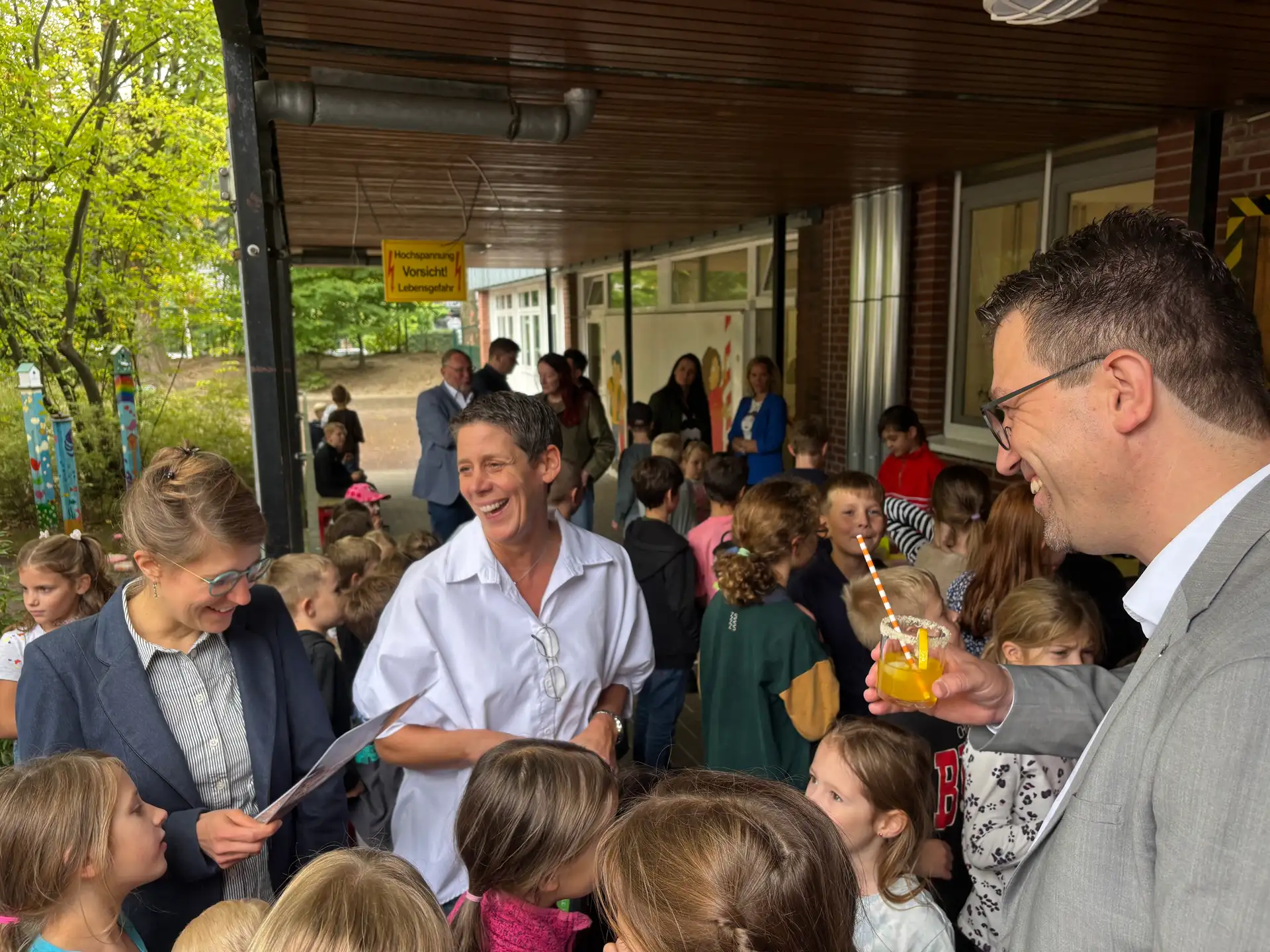 Gruppe von Personen vor dem Schulgebäude während eines Besuchs der Ministerin.