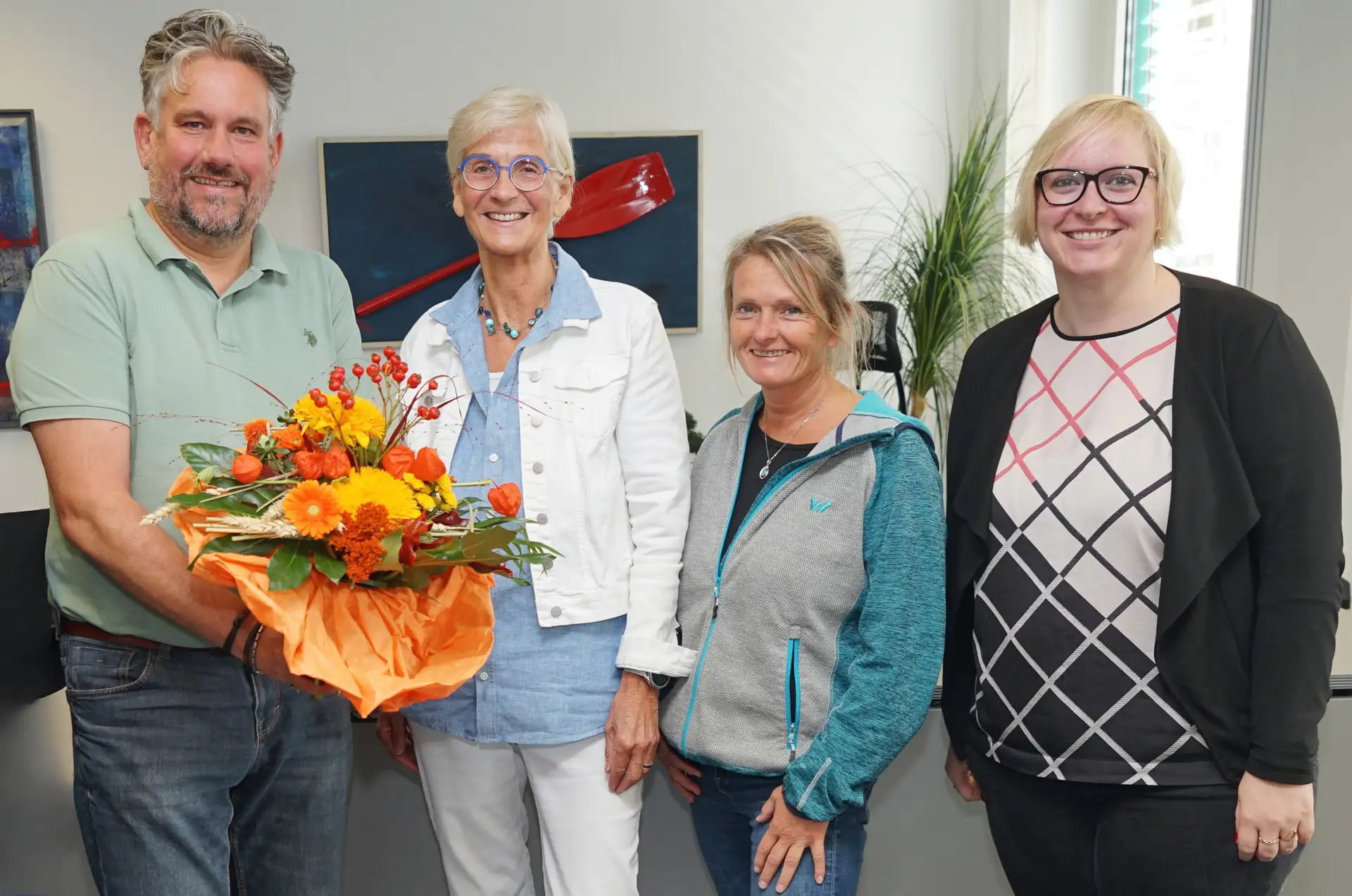 Gruppenfoto zur Verabschiedung von Schulcoach Susanne Wiescher: Vier Personen stehen nebeneinander; im Vordergrund Susanne Wiescher zwischen Christian Benzrath und zwei weiteren Personen.