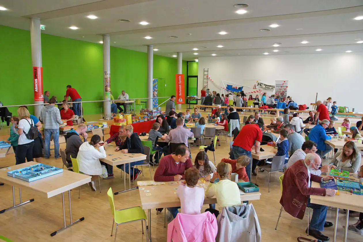 Mann hält Spielmaterial bei einem Familienspielefest.