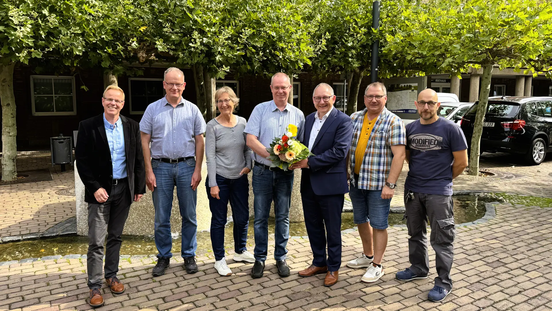 Jürgen Vos (Mitte) wird zu seinem 25-jährigen Dienstjubiläum zusammen mit mehreren Personen im Rathaus gezeigt.