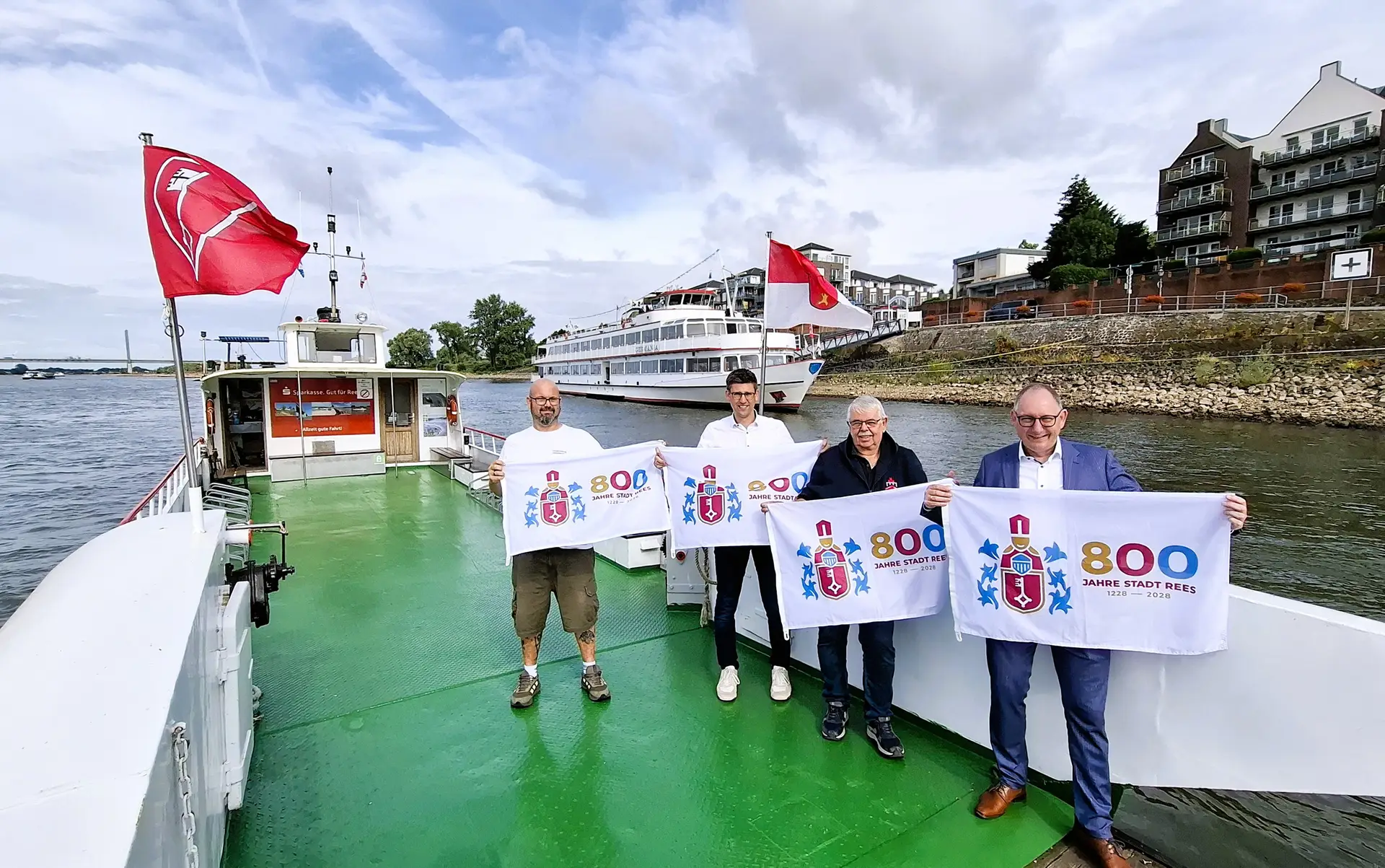 Fahrgastschiff Germania sowie die Rheinfähren Räße Pöntje und Inseltreue B mit der Jubiläumsfahne zum 800-jährigen Stadtjubiläum von Rees; im Vordergrund Sebastian Hense, Rainer van Laak, Jörn Franken und Daniel de Raaf (v. re.).