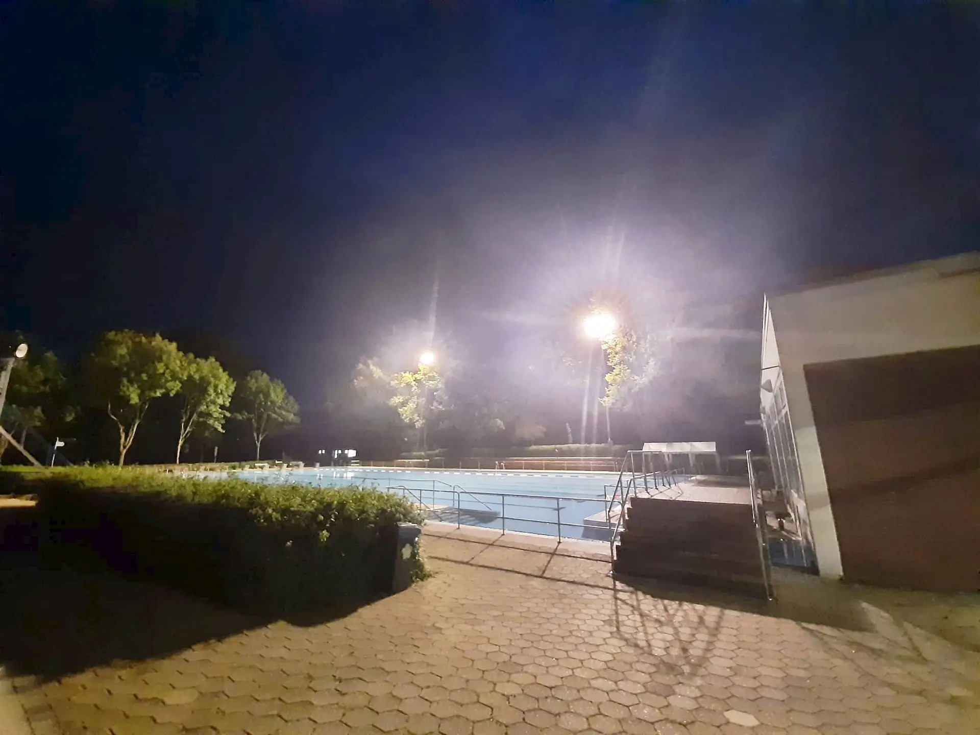 Schwimmer im Wasserbecken bei Flutlichtschwimmen, aufgenommen mit Beleuchtung im Hintergrund.