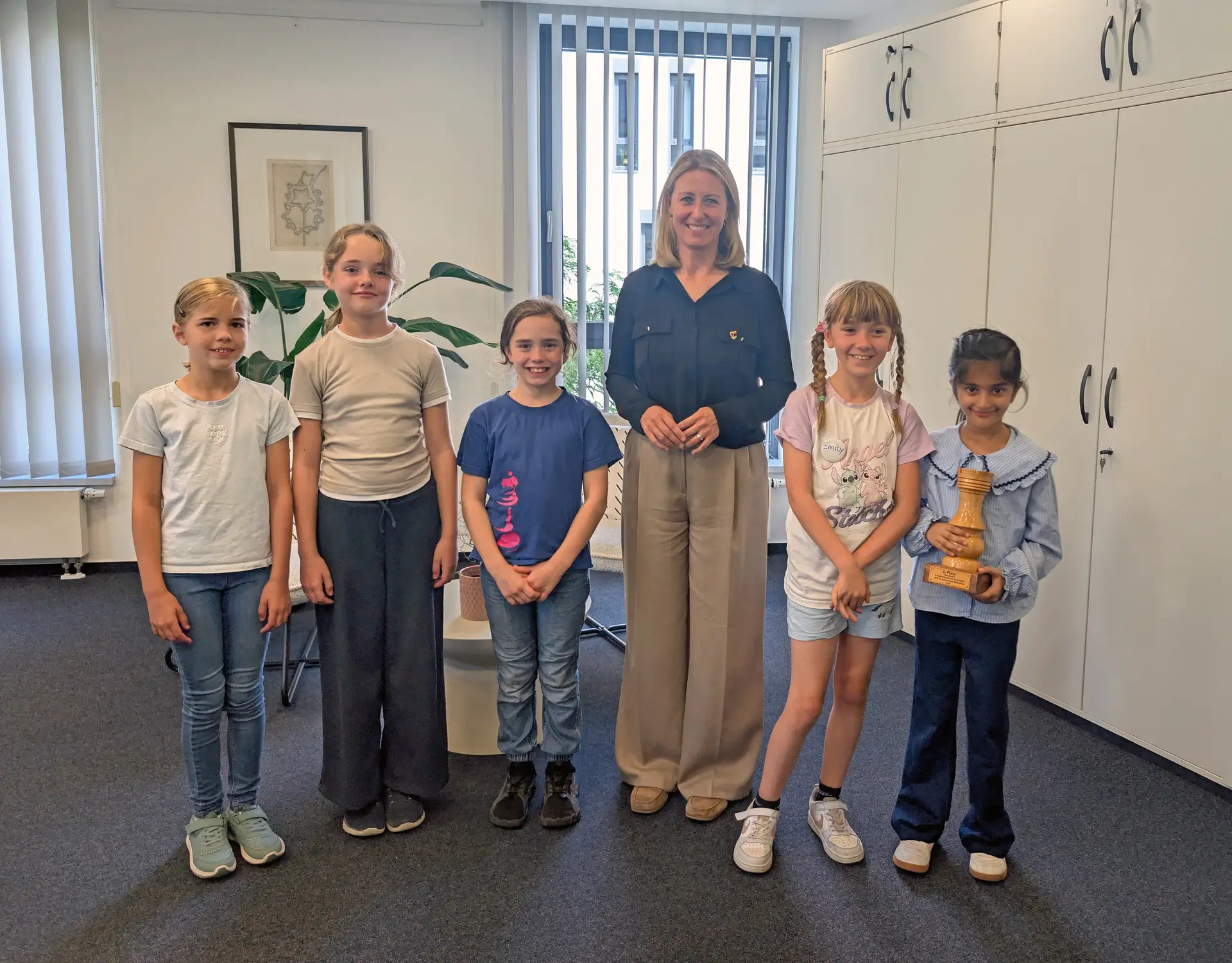 Fünf Mädchen und eine erwachsene Person posieren gemeinsam; die Gruppe wirkt wie bei einer Gratulation zum Erfolg im Schulschach.