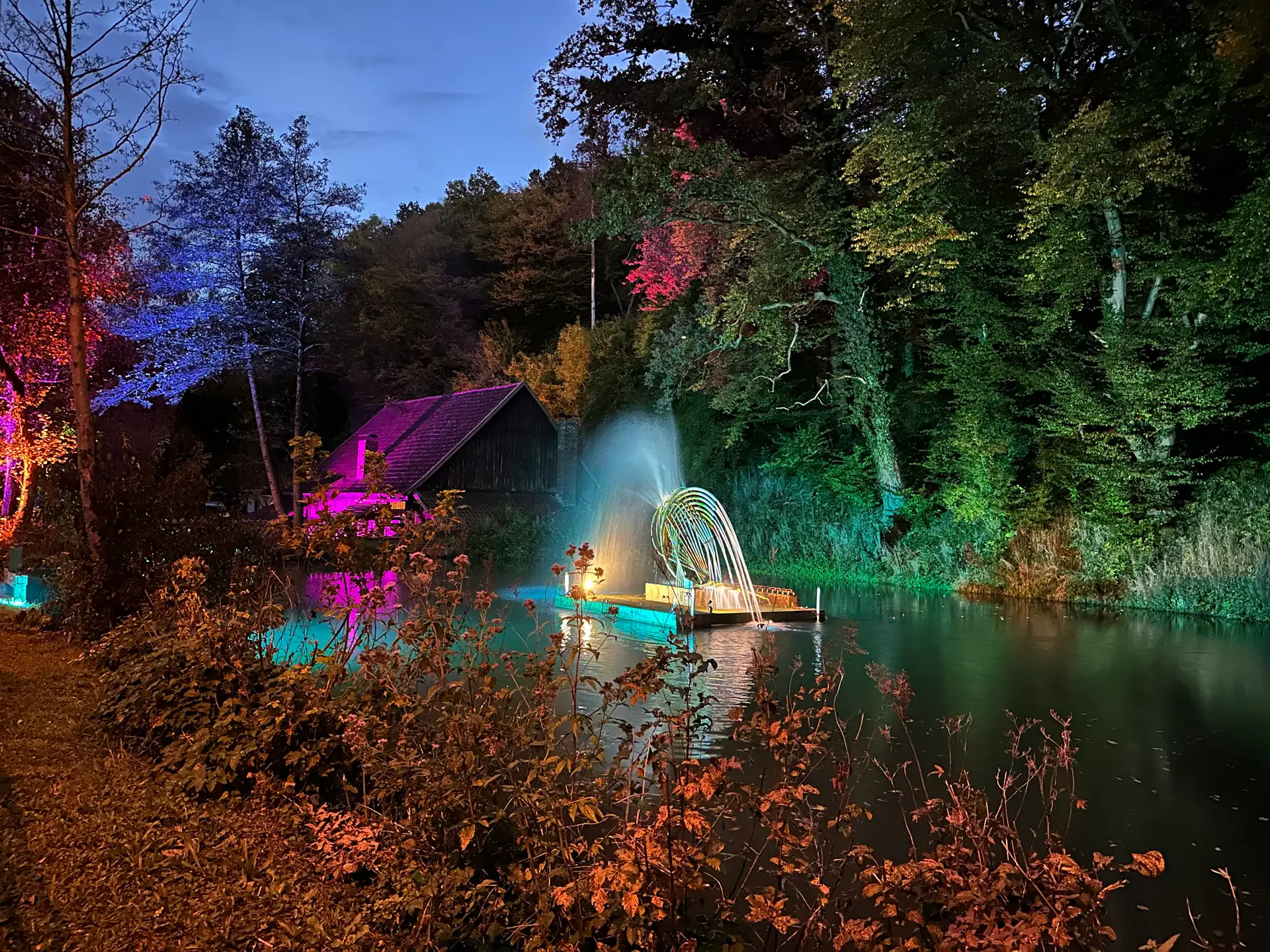 Abendstimmung am Alten Hammer: Ein historisches Industriegebäude ist in buntem Licht beleuchtet.