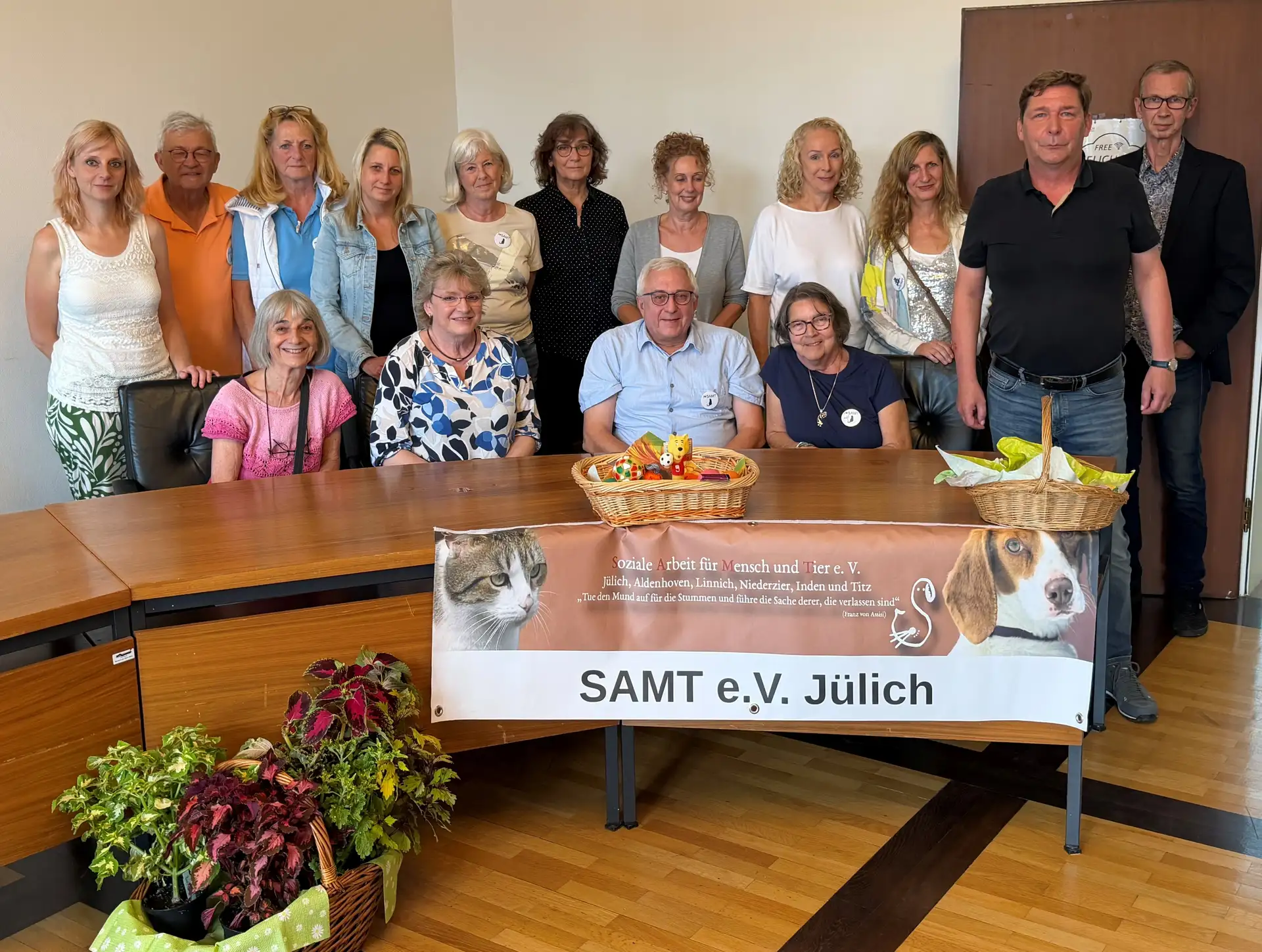 Mitglieder des Vereins Samt e.V. stehen und sitzen hinter einem Tisch mit Vereinsbanner.