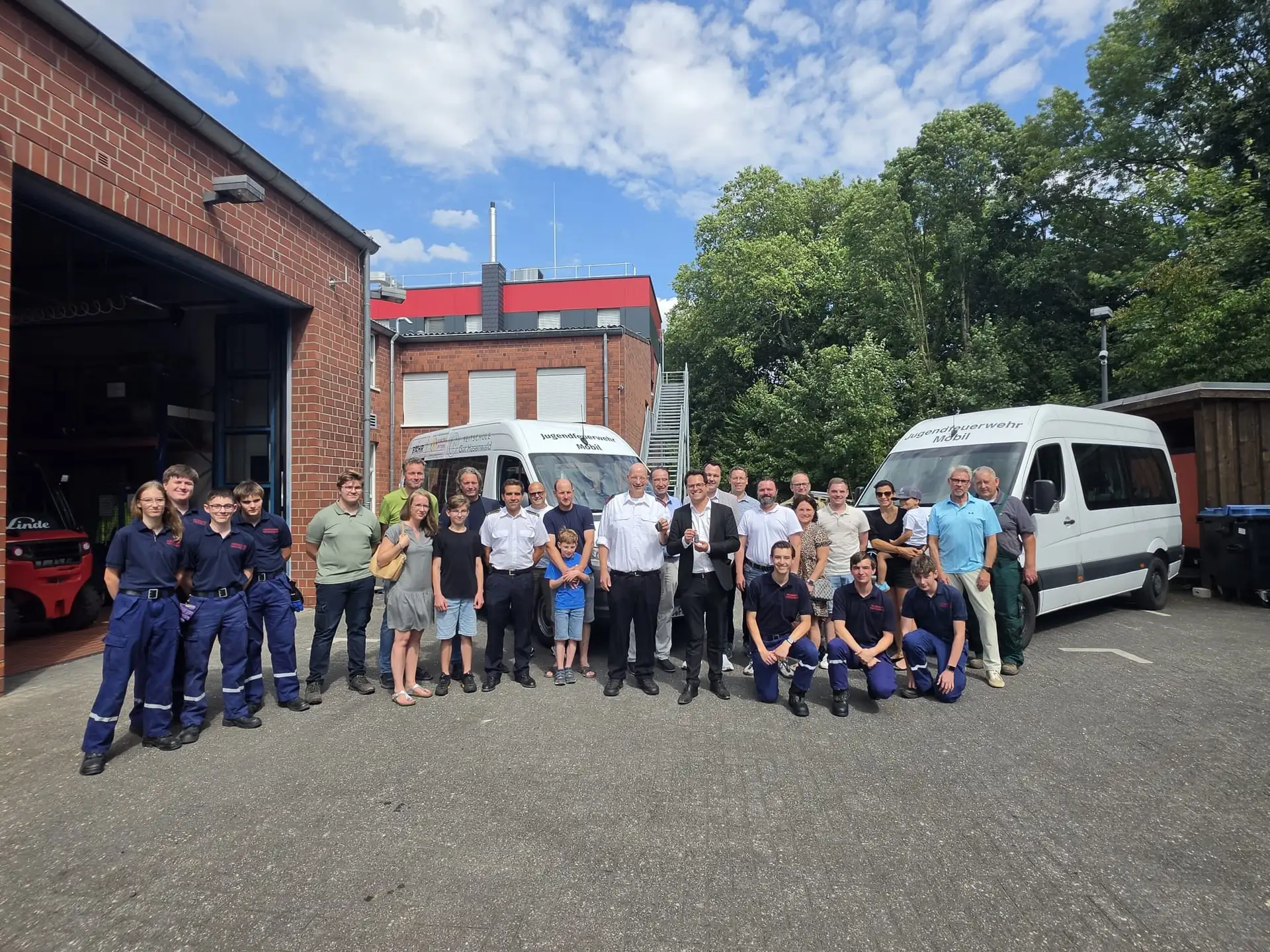 Gruppenfoto mit Verantwortlichen der Feuerwehr, Jugendlichen, Jugendbetreuern, Sponsorenvertretern und dem Bürgermeister bei der Übergabe des Jugendfeuerwehrfahrzeugs.