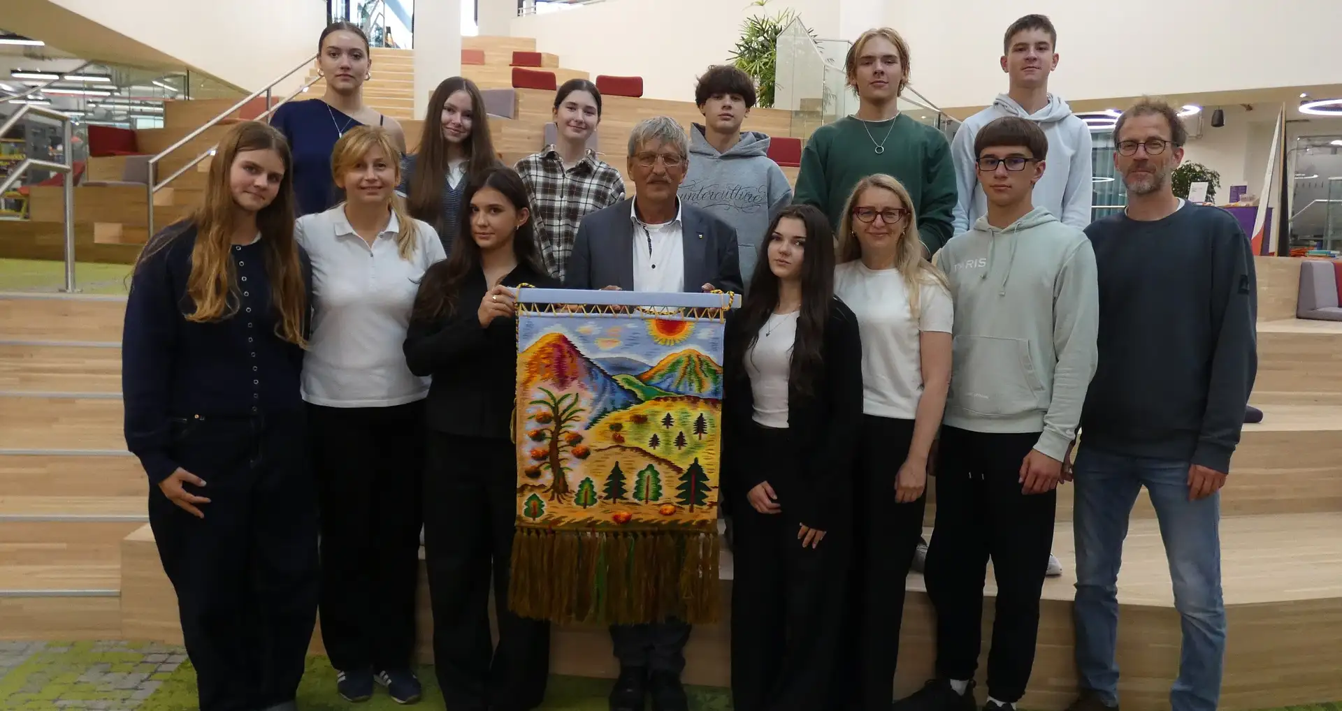 Schülerinnen und Schüler werden im Rathaus empfangen; eine Person spricht die Gruppe im Multifunktionssaal an.