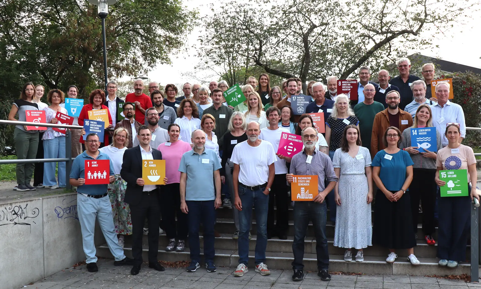 Menschen sitzen in einer Veranstaltung zum Dialogforum zur Ratinger Nachhaltigkeitsstrategie; im Hintergrund sind weitere Teilnehmende und ein Veranstaltungsraum zu sehen.