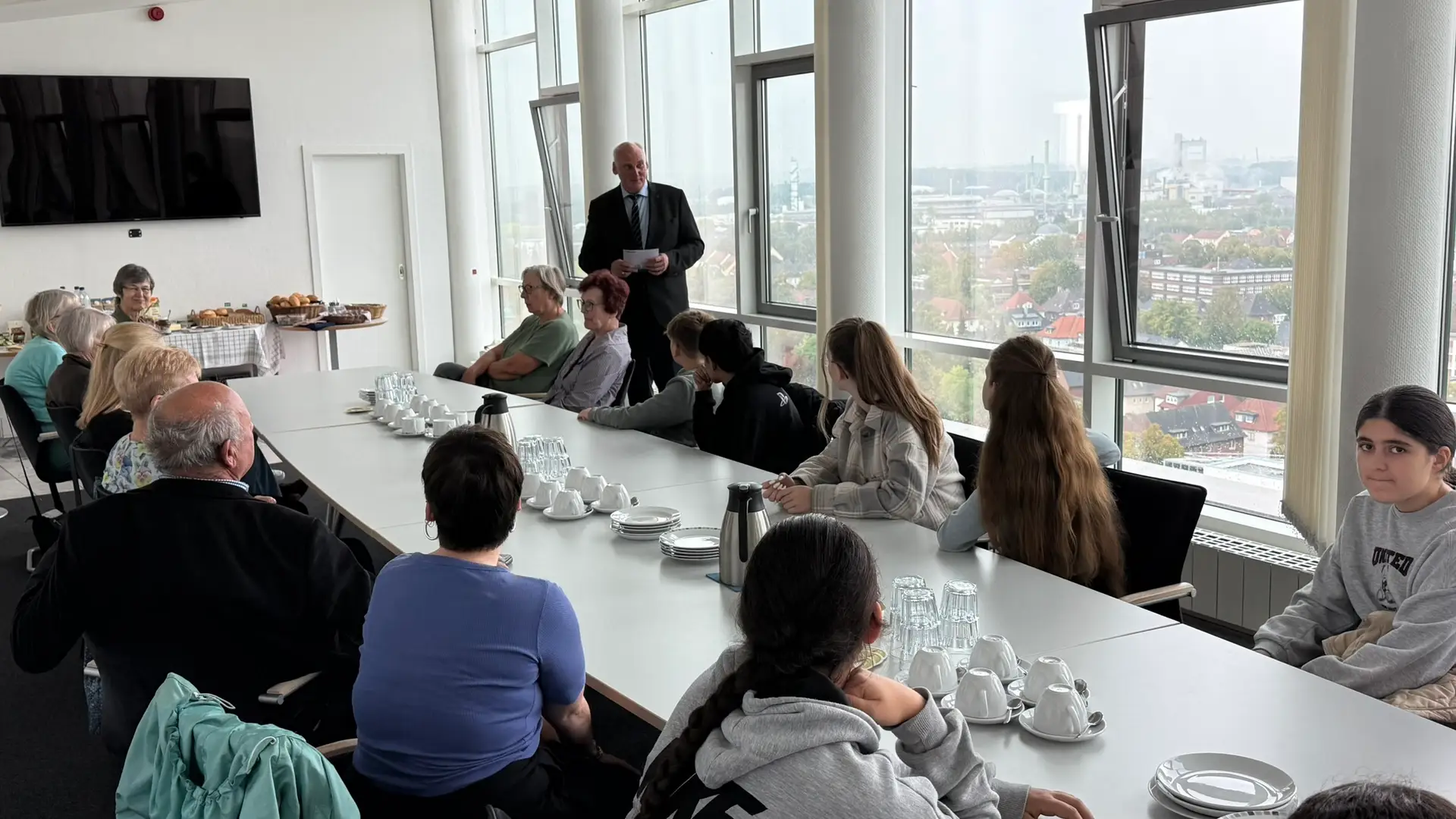 Thorsten Redeker steht vor einer Tischrunde mit Schülerinnen, Schülern und weiteren Gästen im Lüner Rathaus.