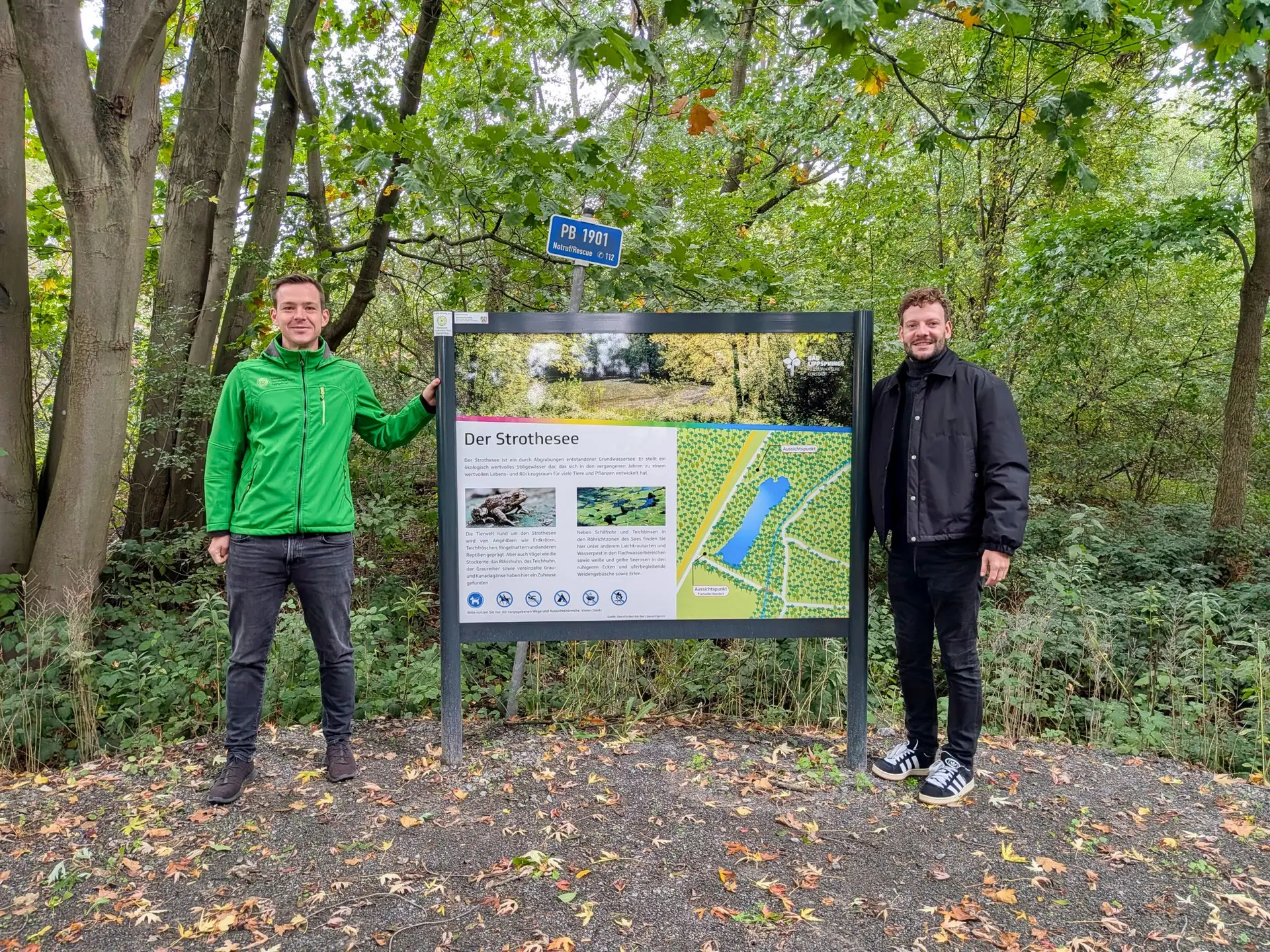 Niklas Hecker vom Stadtmarketing und Rubens Hey vom Naturpark Teutoburger Wald/Egge stehen an den neuen Infotafeln am Strothesee.