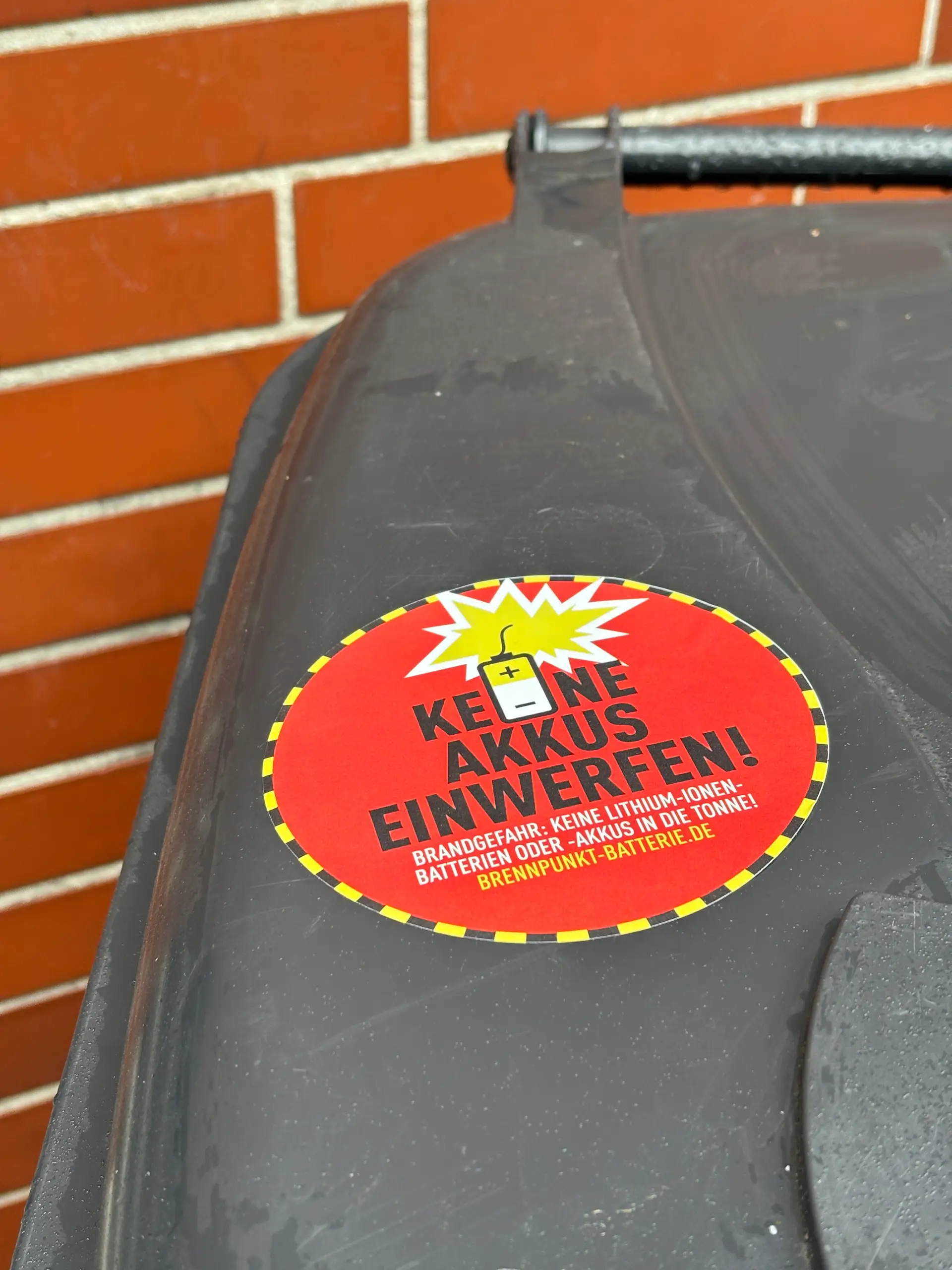 Aufkleber auf Restmülltonnen weisen auf die Brandgefahr durch falsch entsorgte Batterien und Akkus hin.