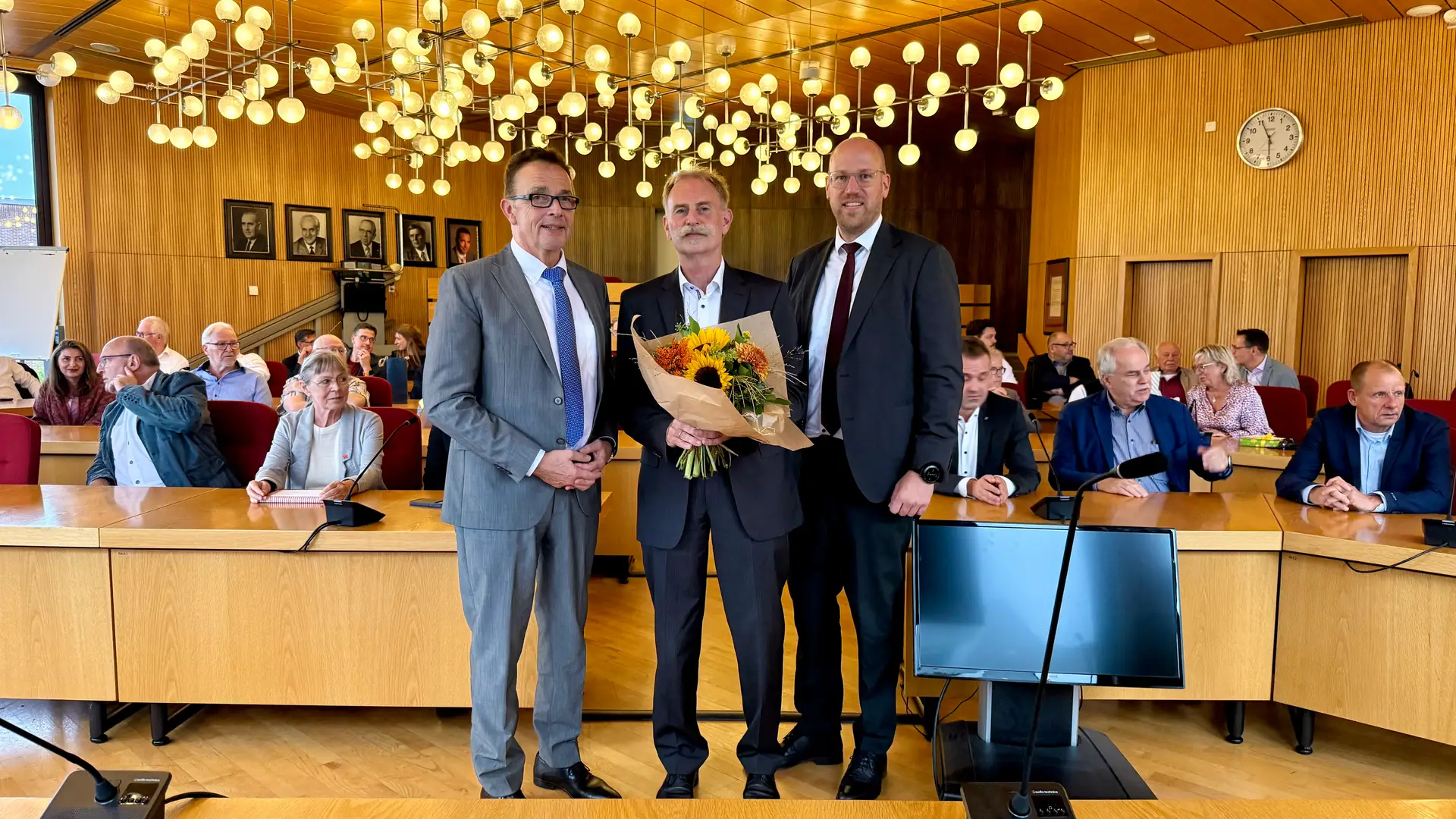 Foto zum Text der Pressemitteilung: eine Gruppe von Personen (u. a. Bürgermeister und der verabschiedete Kämmerer) bei einer offiziellen Verabschiedung im Ratssaal.