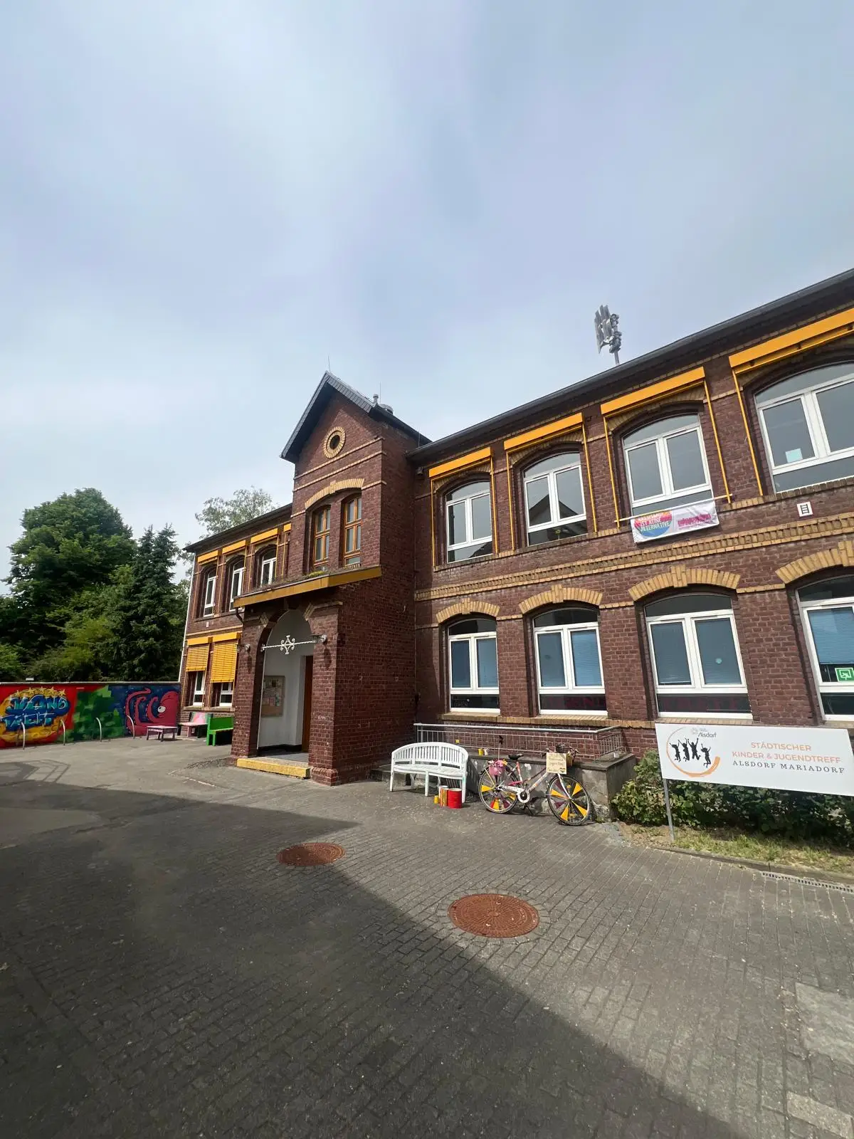 Ein Gruppenfoto im Jugendtreff mit Kindern und Jugendlichen vor einer Wand/mit Freizeit-Umgebung.
