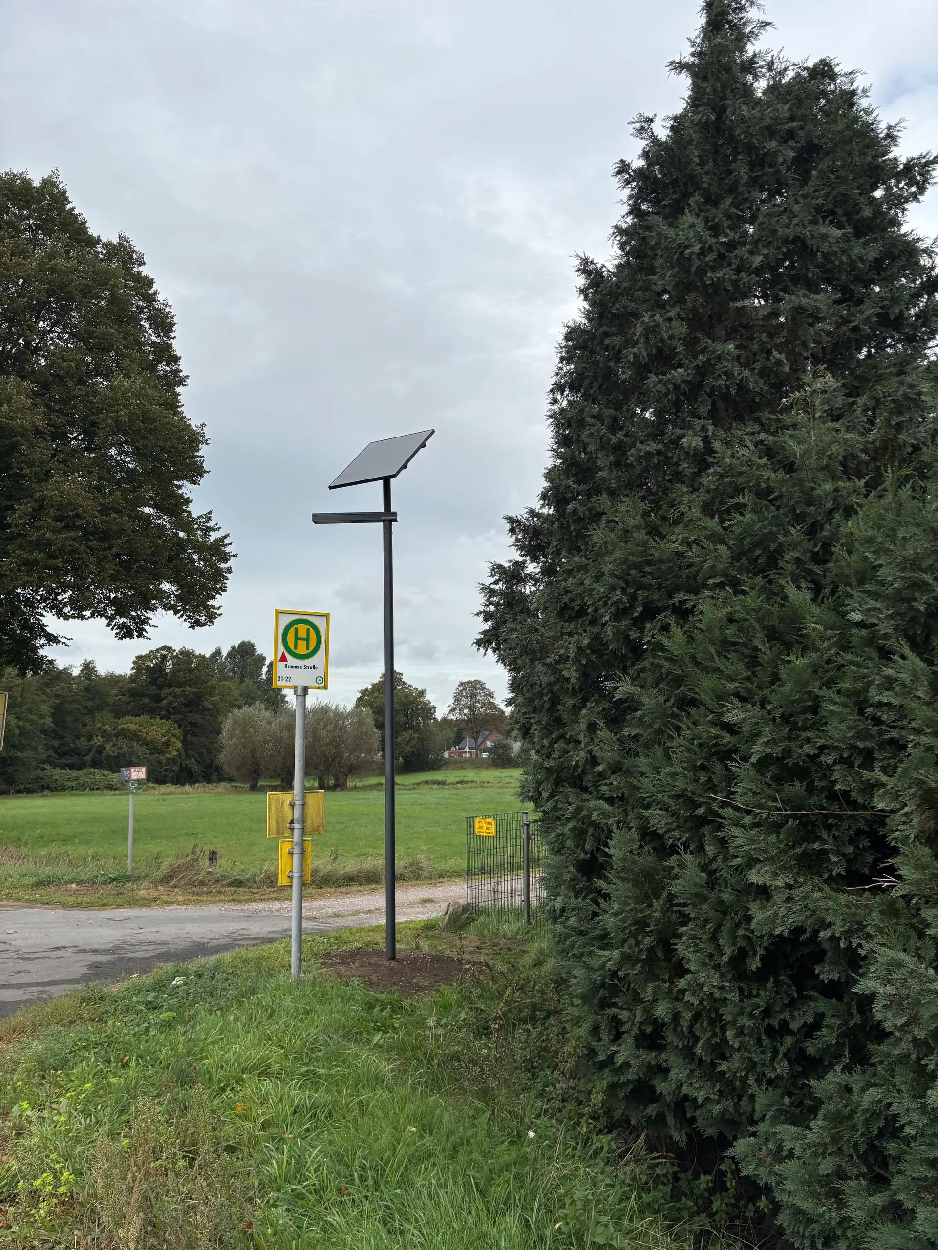 Eine Straßenlaterne, die als Solarleuchte dient, bei nassem Wetter in der Nähe eines Gehwegs.